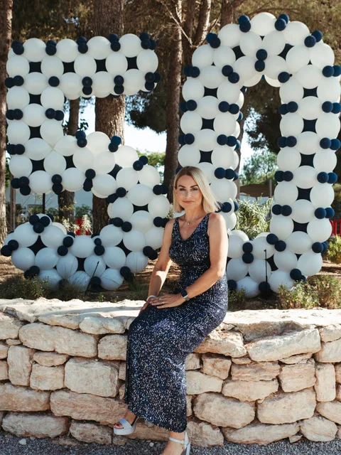 A guest in navy sitting in front of a giant 50 made of white and navy balloons