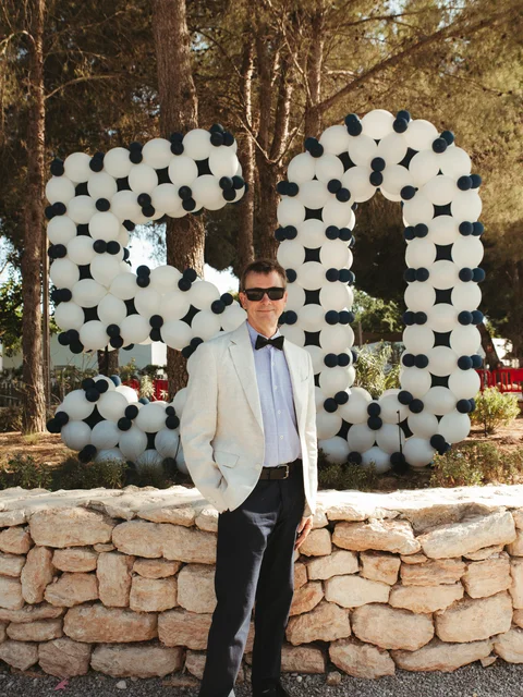 A guest in a white dinner jacket standing in front of the giant balloon 50