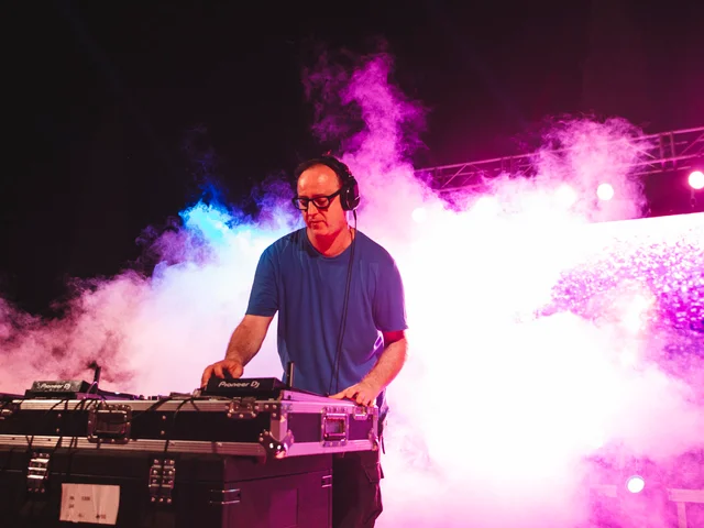 DJ Sasha at the decks surrounded by pink stage smoke