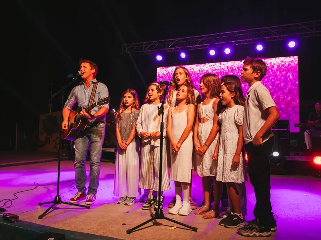 James Blunt playing guitar on stage with the Morna school choir