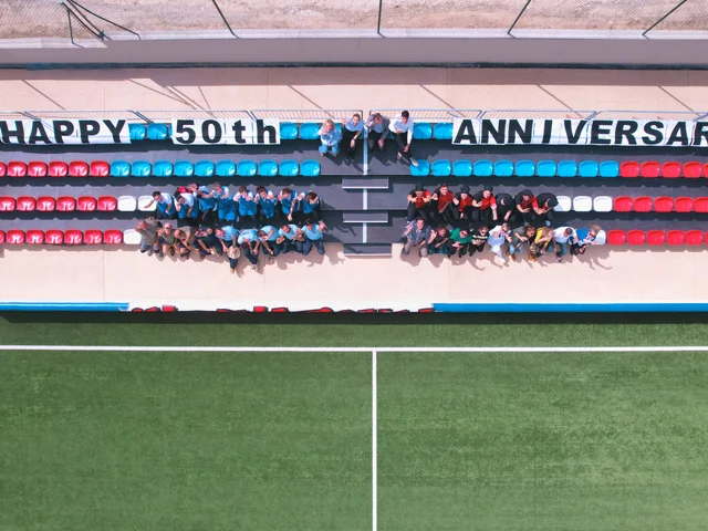 Staff in the stand beneath a Happy 50th Anniversary banner, seen from above