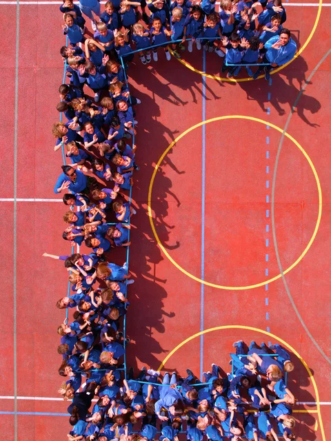 Students in blue forming the letter C on the sports court