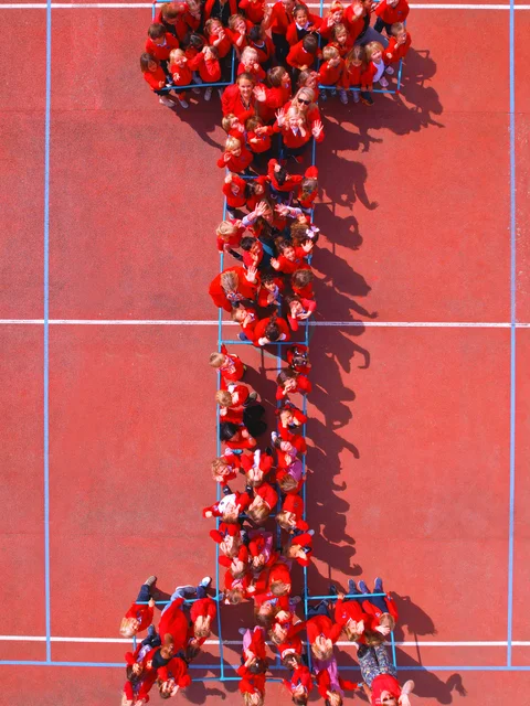 Students in red forming the letter I on the sports court