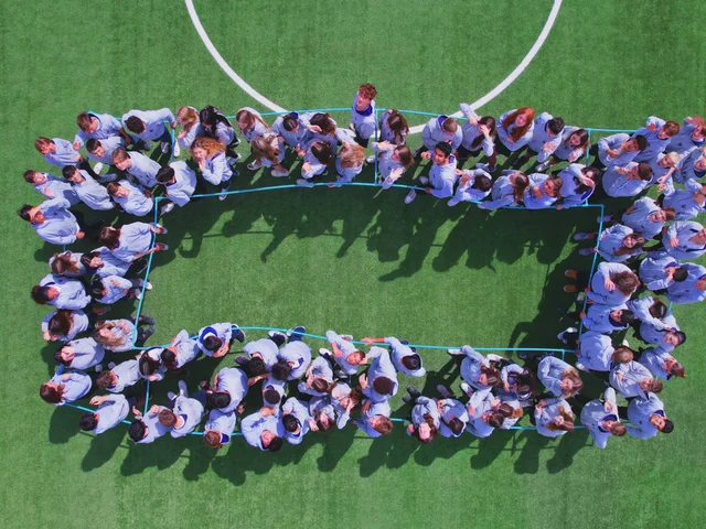 Students in white and navy forming the number 0 on the football pitch