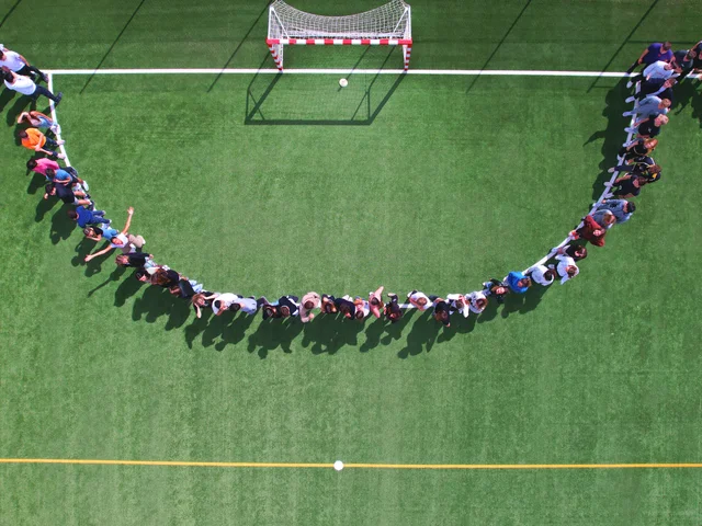 A line of students tracing a curve around the football goal