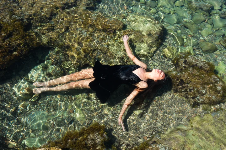 A girl floating on her back in clear shallow water