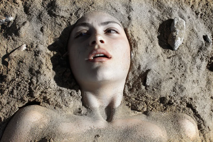 A face emerging from wet sand