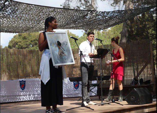 A student holding up a framed photograph on stage during the auction