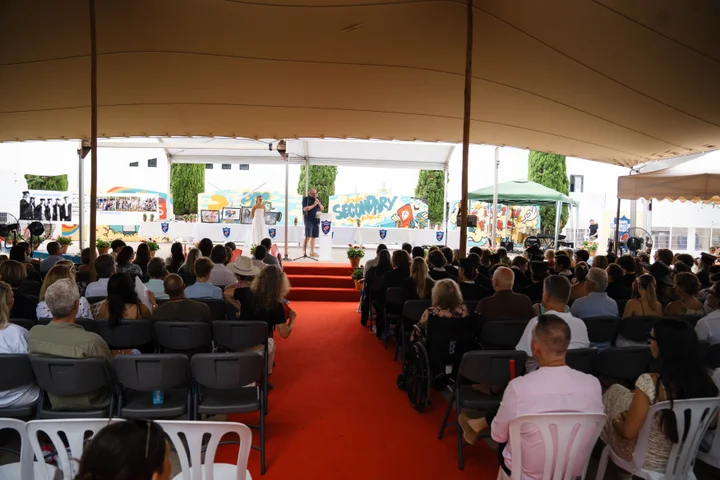 Families seated under the marquee as a framed artwork is presented on stage at the auction
