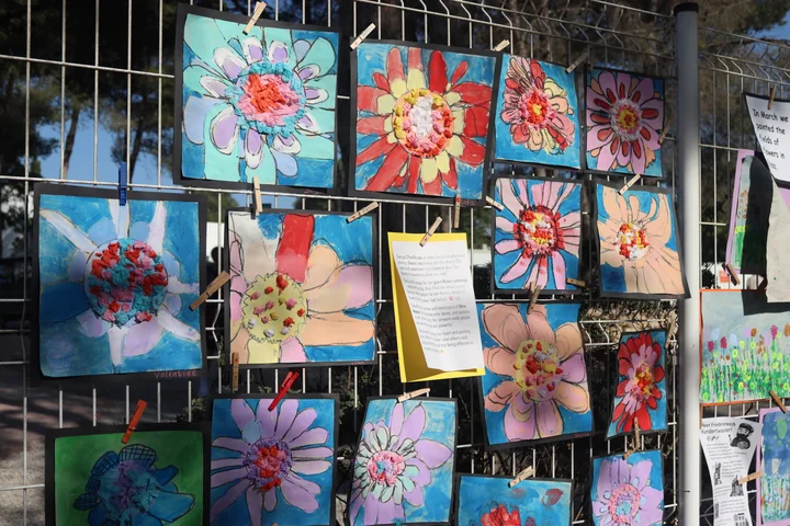 Primary flower paintings pegged to a fence outdoors