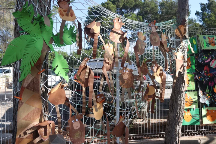 Paper monkeys and palm leaves hanging from a net in the trees