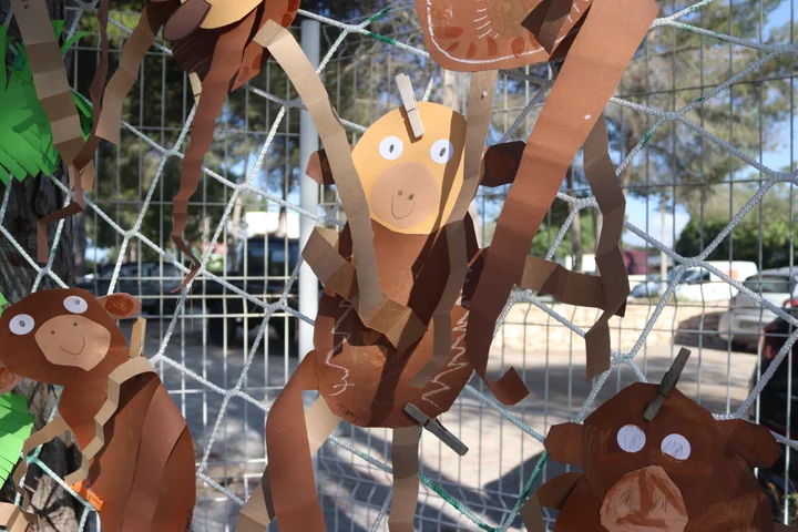 Close-up of cut-paper monkeys swinging on a rope net