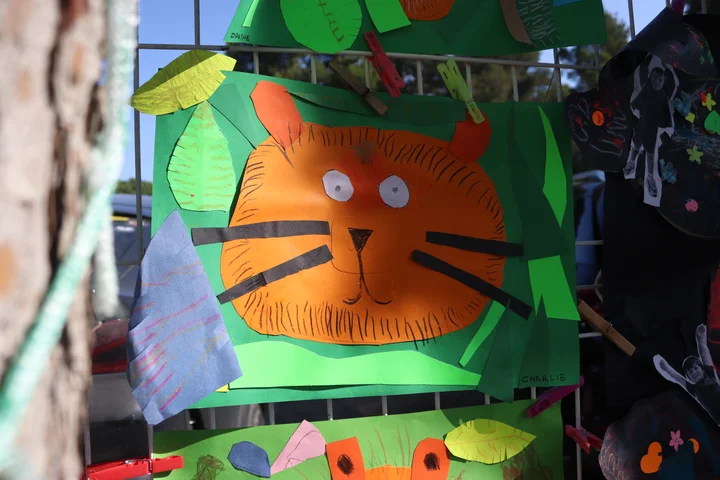 A cut-paper tiger face among jungle leaves