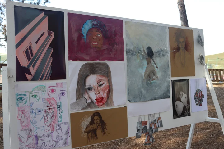An outdoor board of portraits and drawings