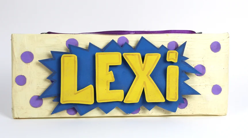 A wooden name sign reading LEXI