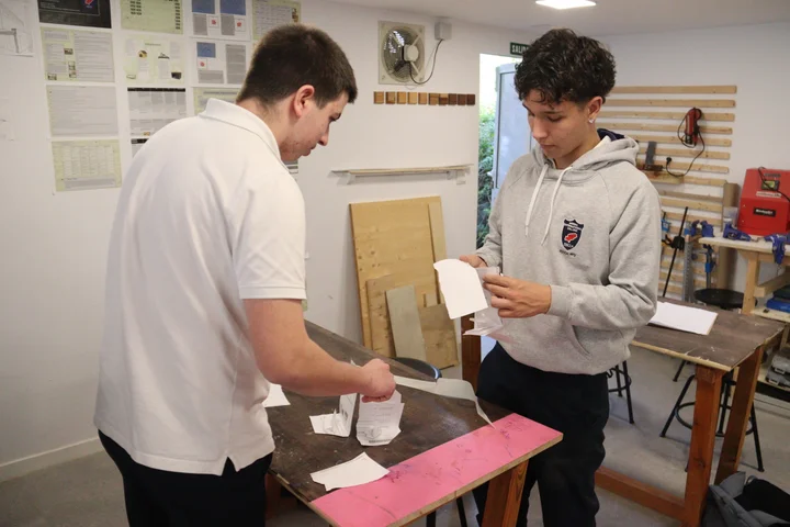 A teacher helping a student build a paper structure