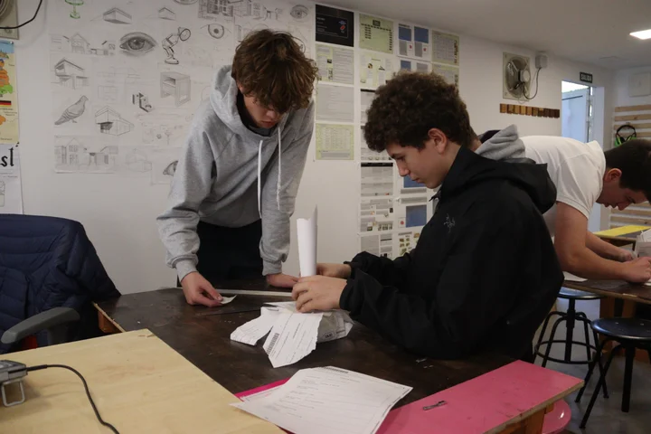 Students testing paper columns at a workshop bench