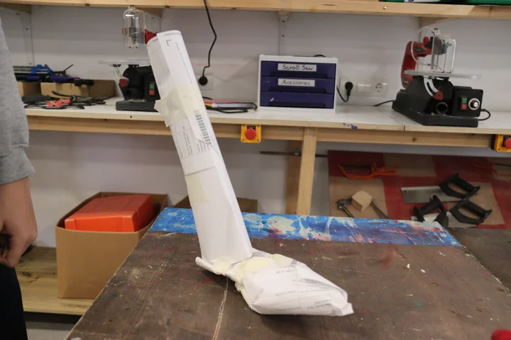 A tall paper tower standing on a workbench