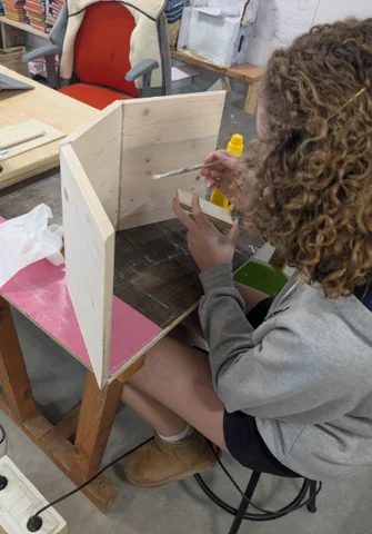 A student gluing the panels of a wooden box