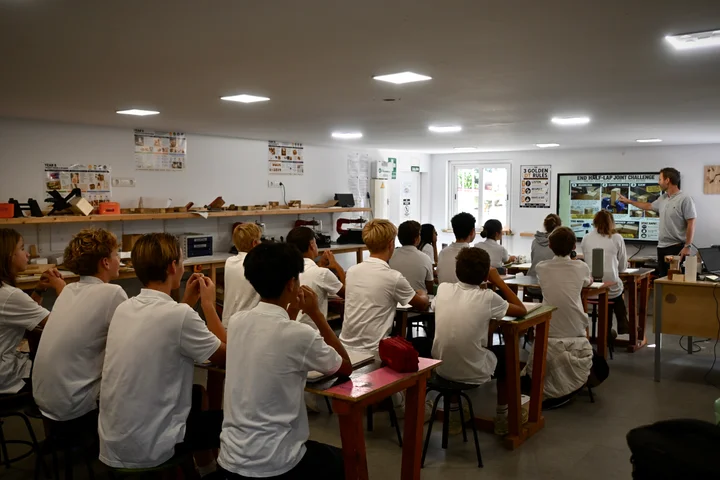 A Year 7 Design & Technology class watching their teacher at the front of the workshop