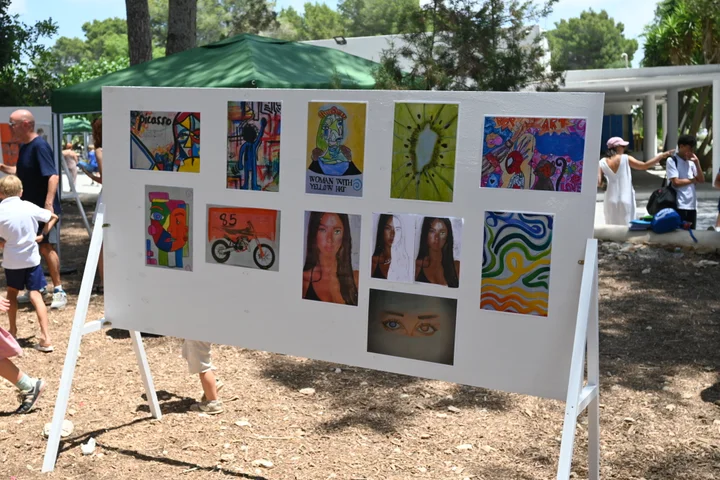 A display board of student paintings outdoors at the exhibition