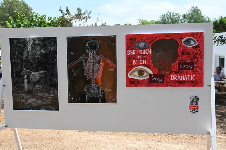 Paintings and mixed-media work on display under the pines