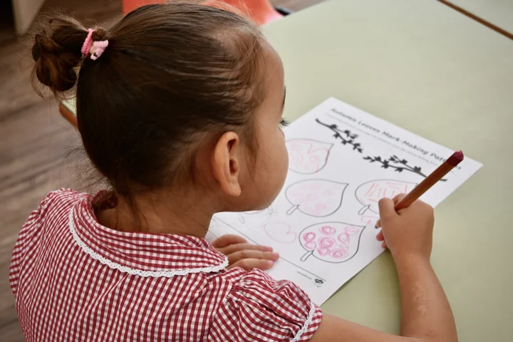 A pupil decorating leaf shapes with pink pencil patterns