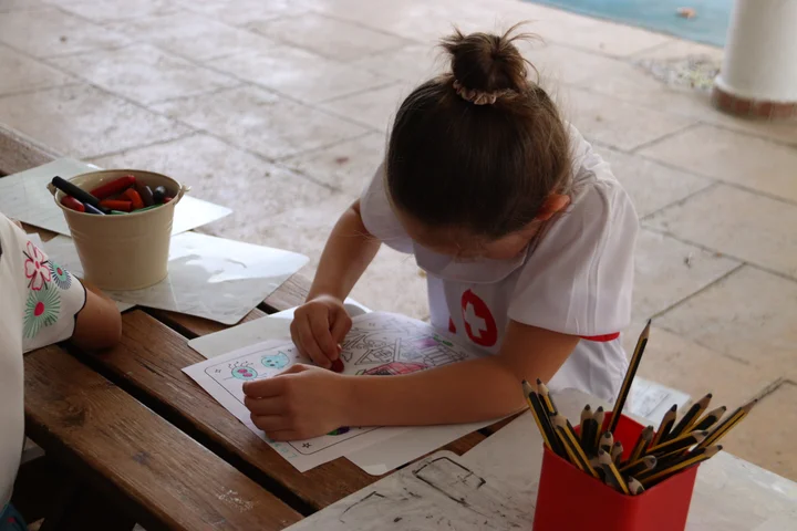 A child in fancy dress colouring at an outdoor table