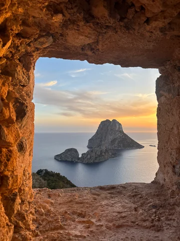 Es Vedrà framed through a rock window at sunset