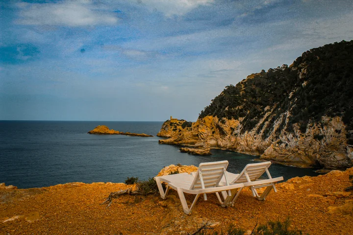 Two sun loungers on a clifftop above the sea