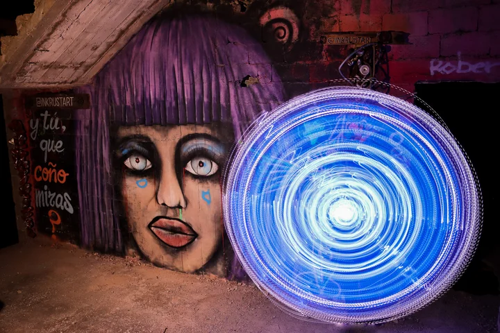 Light painting: a swirling blue circle beside a mural of a face with purple hair