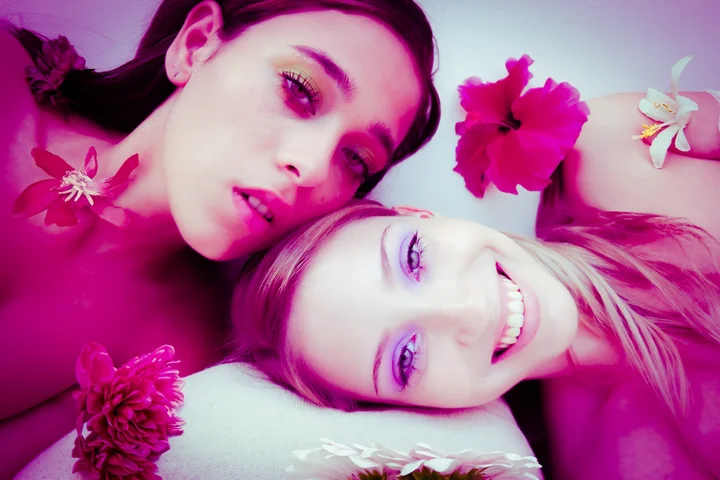 Two girls lying together with pink flowers in their hair