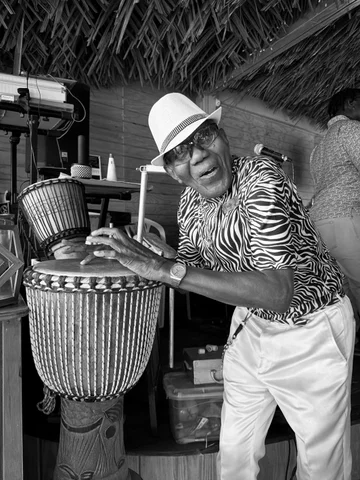 Black and white portrait of a man playing a djembe drum