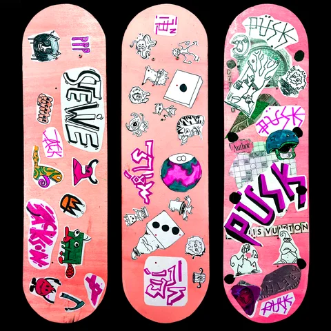 Three pink skateboard decks covered in hand-drawn stickers