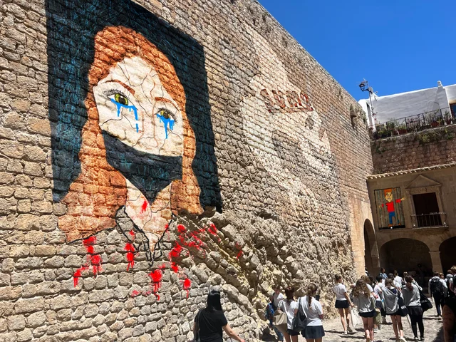 A large mural portrait of a woman on the old town walls