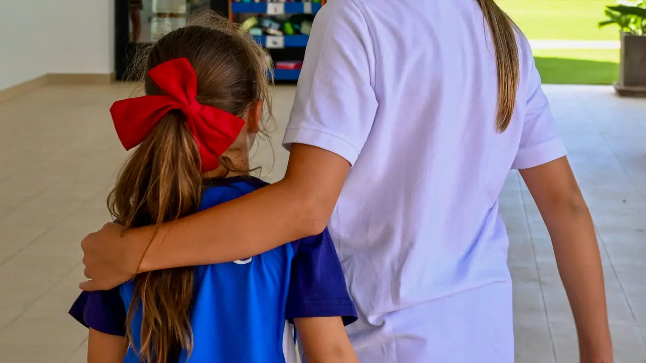 An older Morna student walking with her arm around a younger pupil's shoulders