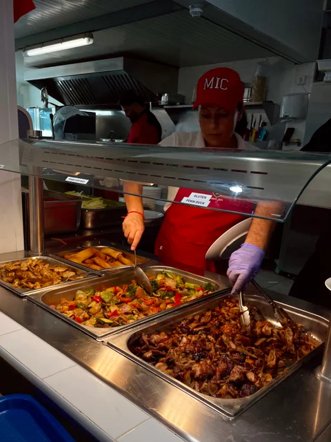 Kitchen staff serving hot dishes from the buffet counter