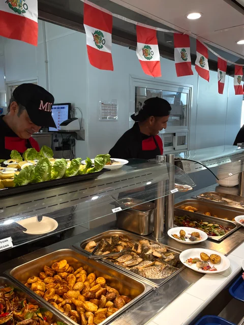 The buffet counter under Peruvian flags, with hot dishes and salads