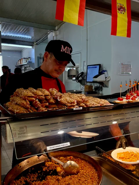A chef serving paella at the buffet counter under Spanish flags