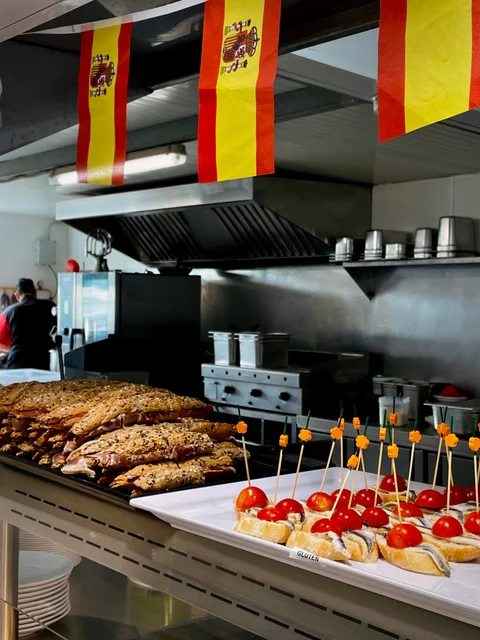 Fish and tomato skewers on the buffet counter under Spanish flags