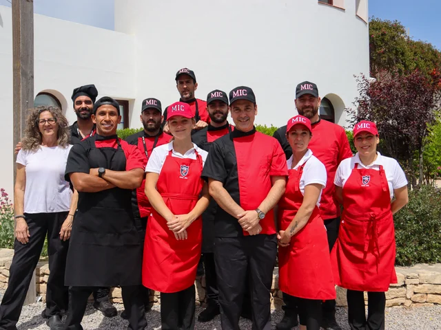 The Morna kitchen team in red and black chef's uniforms outside the school