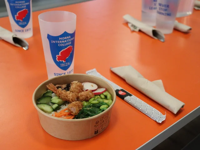 A poke bowl with tempura prawns and edamame on a dining room table