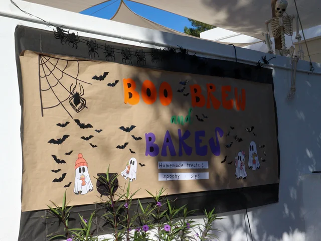 The Boo Brew and Bakes banner decorated with bats and a spider web