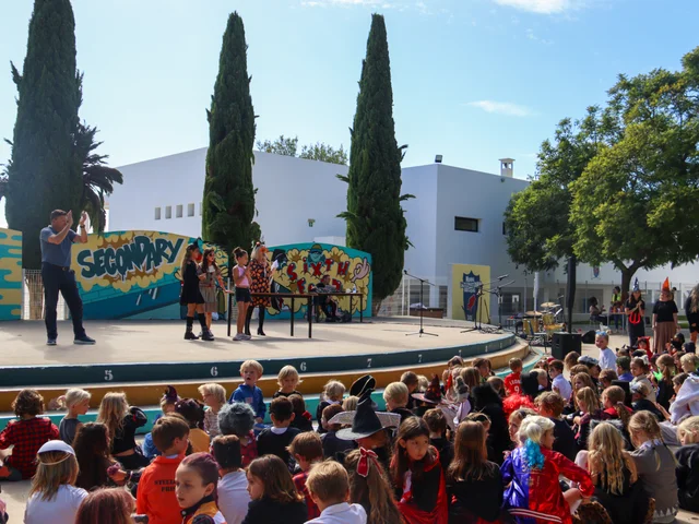 Pupils in costume watching a performance on the outdoor stage