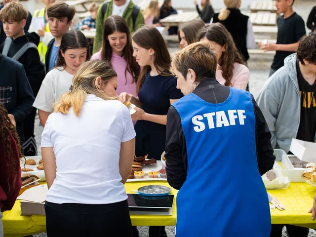 Students crowding round the cake stall, served by a member of staff