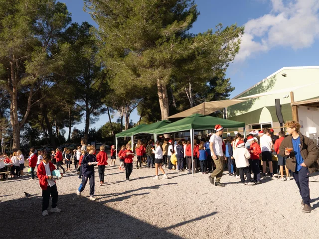 Families and students under the trees at the Christmas cake sale