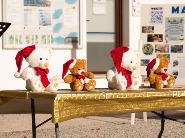 Teddy bears in Santa hats on a gold table at the Christmas sale