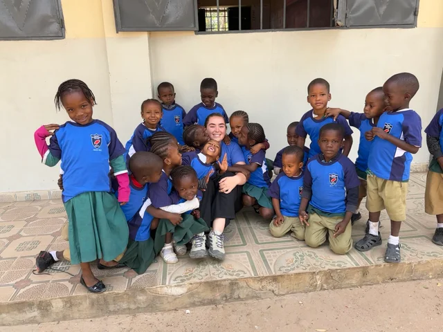 A Morna student sitting with a group of young children in The Gambia