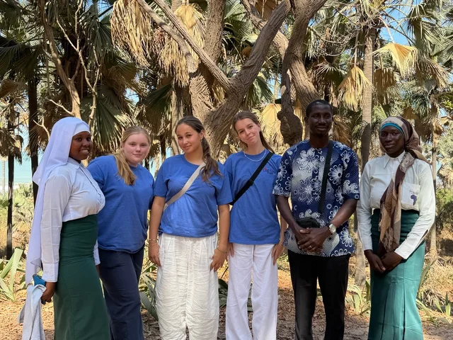 Morna students with their Gambian hosts under the palm trees