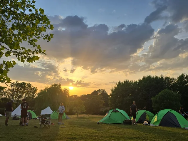 Expedition tents pitched in a field at sunset